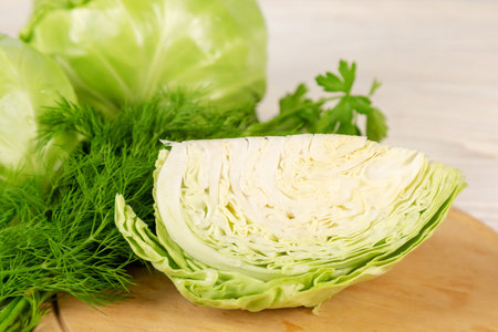 Fresh white cabbage and green vegetables for salad on a wooden cutting board. Vegetarian and healthy diet food concept.の写真素材