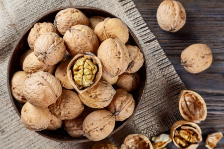 Walnuts on a brown wooden background. Whole nuts in a coconut bowl. Top view
