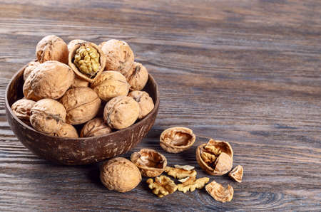 Walnuts on a brown wooden background. Whole nuts in a coconut bowlの写真素材