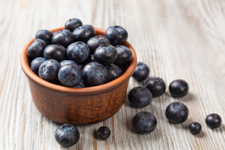 Fresh blueberries in a brown plate on a wooden background. Summer still life with berriesの写真素材