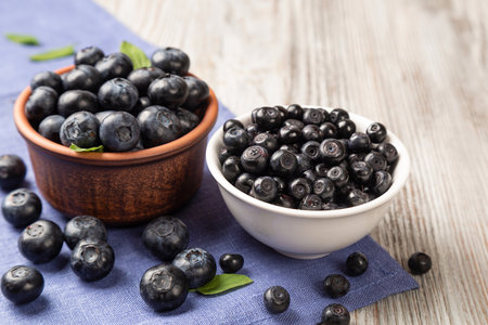 Fresh large and small blueberries in a brown and white plate on a wooden background.の写真素材
