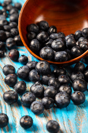 Scattered blueberries from a wooden bowl on a blue backgroundの写真素材