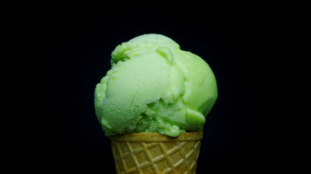 Scoop lime flavoured sherbet ice cream in waffle cone on black background, Closeup Front view Food concept.            の写真素材
