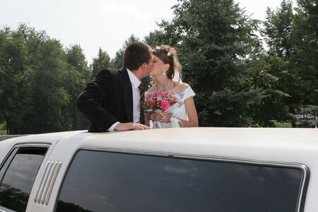 Bridegroom and bride are kissed in limousineの写真素材