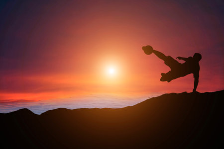 Silhouette of a man playing soccer in golden hour sunsetの写真素材
