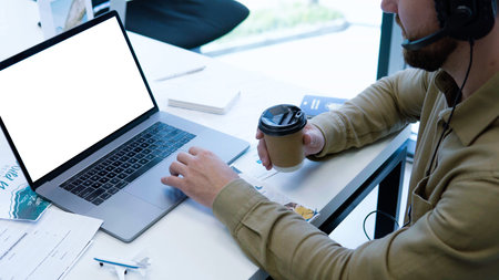 Cropped image of businessman working with blank white screen computer laptop while holding cup of...