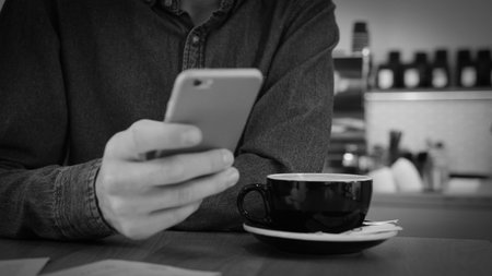 Cropped shot of young man handwriting on laptop while working in black office room.の写真素材