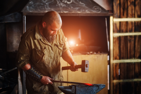 Blacksmith working in the forge. Manufacture of parts  from molten metal, using the hammer and anvil.の写真素材