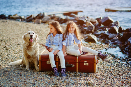 Two little twin sisters on a walk with dog の写真素材