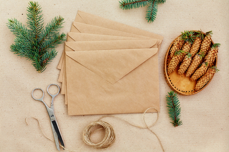 Christmas gifts and letters handmade, and everything necessary for them. Envelopes of Kraft paper, scissors, spruce cones and jute cord. The view from the top.の写真素材