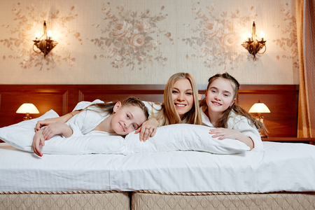 Portrait of a happy mother and her children lying on a bedの写真素材
