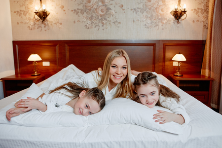 Portrait of a laughing mother and her twin children lying on a bの写真素材
