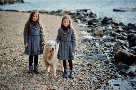 Two little twin sisters on a walk with dog