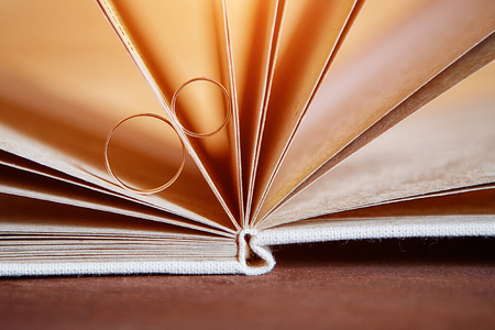 Gold wedding rings in a book made by hand from natural materialsの写真素材