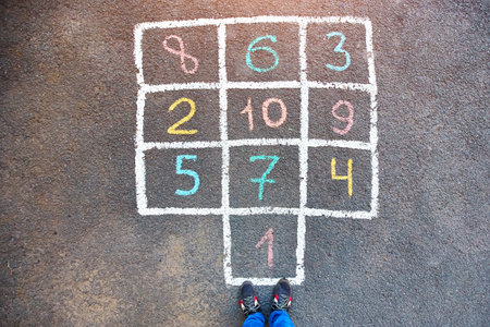 Closeup of hopscotch drawn with chalk on asphalt road. Children games and outdoor activities.