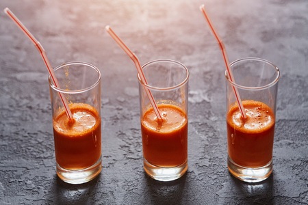 Glasses with freshly squeezed carrot juice on a dark stone backgroundの写真素材