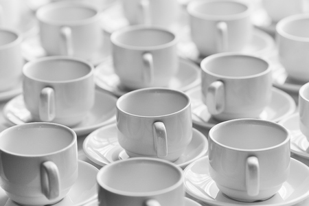 White cups for tea  stacked in line on table with tablecloth for coffee-breakの写真素材
