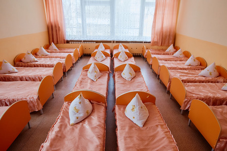 Cots in the kindergarten. Orphanage or boarding school. Beds in a boarding school or in an orphanageの写真素材