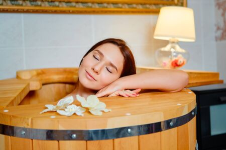 Healing spa treatment. Cedar barrel. Young beautiful girl. Health accessories. Salon procedureの写真素材