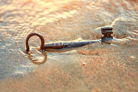 An old lost key in the sand is a newfound opportunity. The concept of success, luck and unexpected wealth.の写真素材