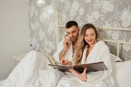 Couple with menu calling room service for food from hotel room.