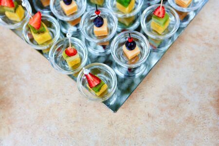 Assorted canapes of fruit and cheese on a glass platter on the background of glasses and champagne. Catering.の写真素材