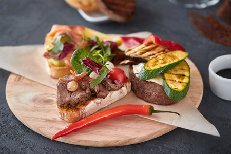 Assorted Bruschetta with fish, meat, vegetables and cheese on a wooden Board. Traditional Italian...