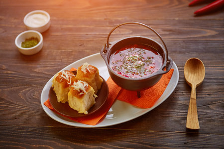 Traditional Ukrainian Russian vegetable borscht on an old wooden background in portioned cast iron....