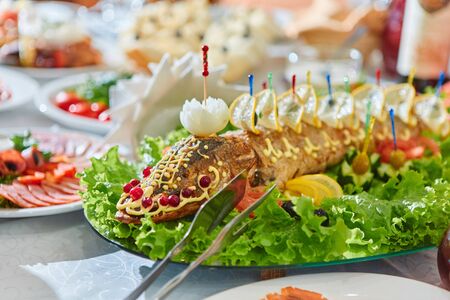 Russian national cuisine-stuffed pike on an oval dish, cooked baked fish, decorated with herbs, lemons, cranberries.の写真素材