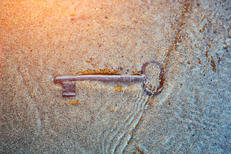 The sea washed up on the sandy beach an old vintage key to a treasure chest. The concept of success, luck and wealth.の写真素材