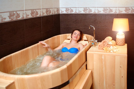 A woman rests in a wooden bath made of cedar.