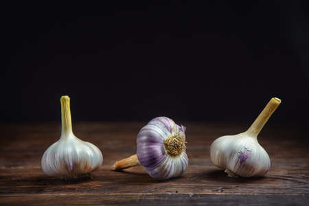 Horizontal view of three garlic heads on a black wooden backgroundの写真素材