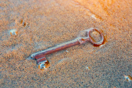 The sea washed up on the sandy beach an old vintage key to a treasure chest. The concept of success, luck and wealth.の写真素材