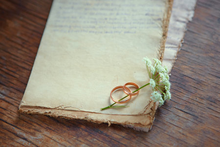 Wedding rings and a wild flower are on antique paper. Symbols of eternal love. Recognition on...