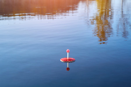 red fishing circle made of foam, floating on the water in the pond waiting for the bite of predatory...