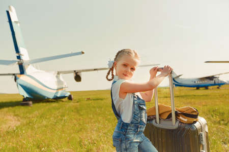 A little girl with a suitcase on the tarmac is going to travel by plane.の写真素材