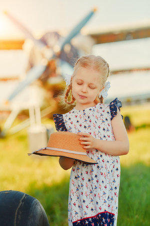 A little girl stands near the plane and dreams of flying it on a tripの写真素材