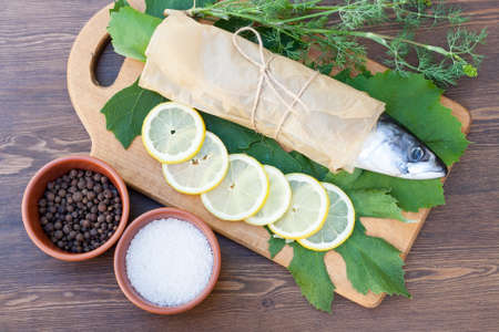 Fresh mackerel on paper in grape leaves with lemon slicesの写真素材
