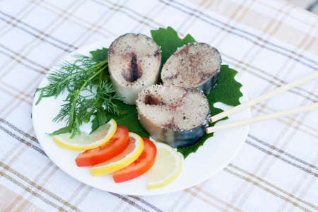Pieces of fresh mackerel in spices with vegetables on white plateの写真素材