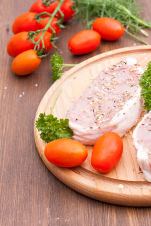 Fresh Raw Steak Meat with spaces herbs and vegetables on wooden tableの写真素材