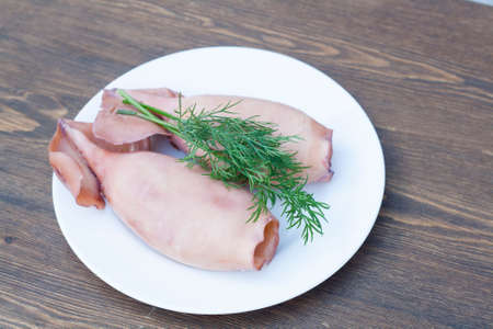 Boiled squid with green dill on a white plateの写真素材