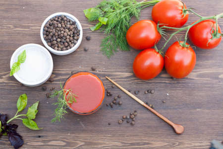 Tomato juice tomatos herbs and spices on wooden tableの写真素材