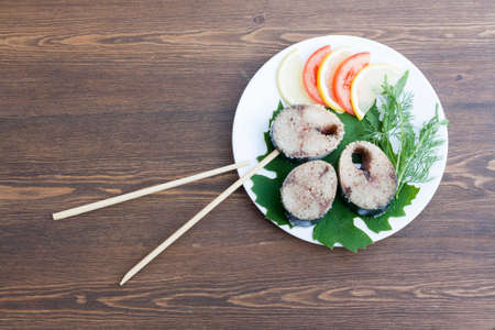 Pieces of fresh mackerel in spices with vegetables on white plateの写真素材