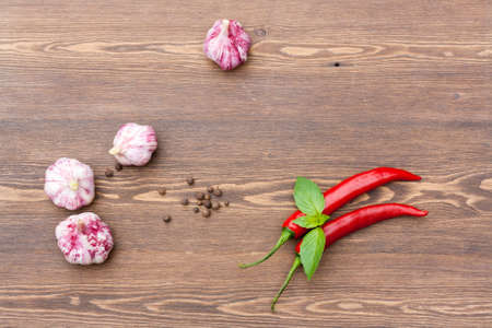 Red chilli pepper and garlic with green basil on wooden tableの写真素材