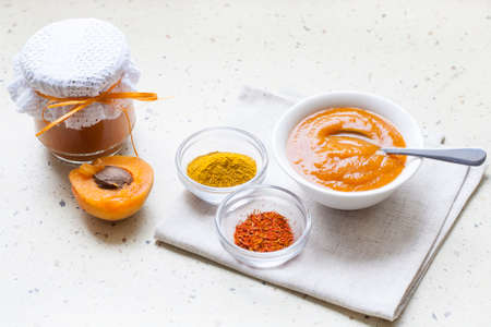 Apricot curry in a glass jar, spices and fresh apricots, selective focusの写真素材
