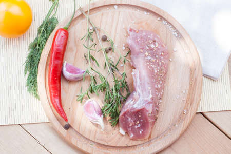 Raw pork tenderloin with spices on a wooden board, selective focusの写真素材