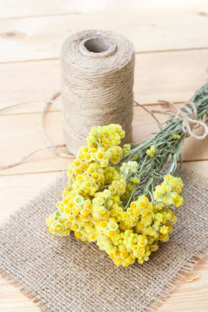Dwarf everlast flowers bouquet, napkin and twine bobbin on light wooden table, selective focusの写真素材