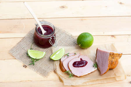 Home made organic cherry jam confiture, smoked meat, rosemary and lime on a wooden tableの写真素材