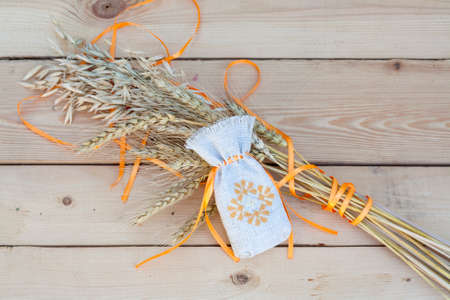 Sachet with ukrainian embroidery, wheat and oat on wooden backgroundの写真素材