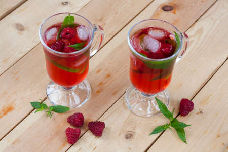 Raspberries fresh drinks with ice and mint on wooden table, selective focusの写真素材